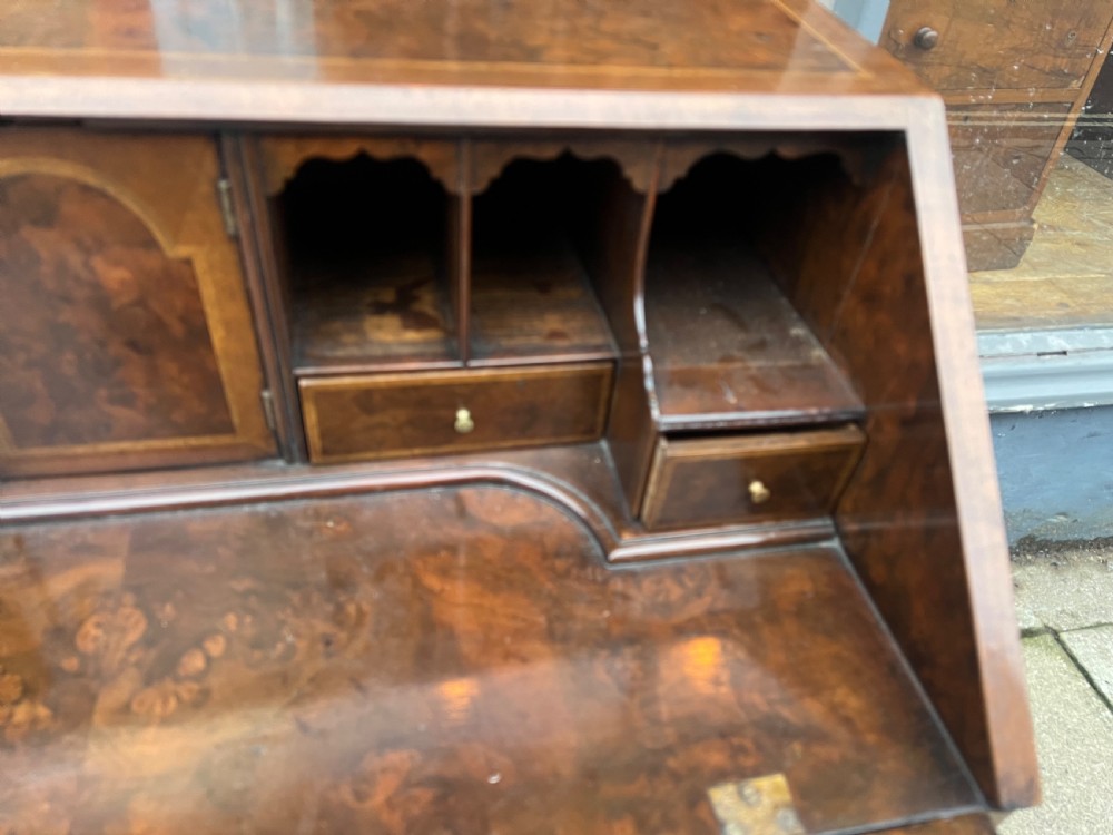 An 18th-century walnut and burr walnut slant-front bureau featuring crossbanded drawers, brass drop handles, and bracket feet. View VI