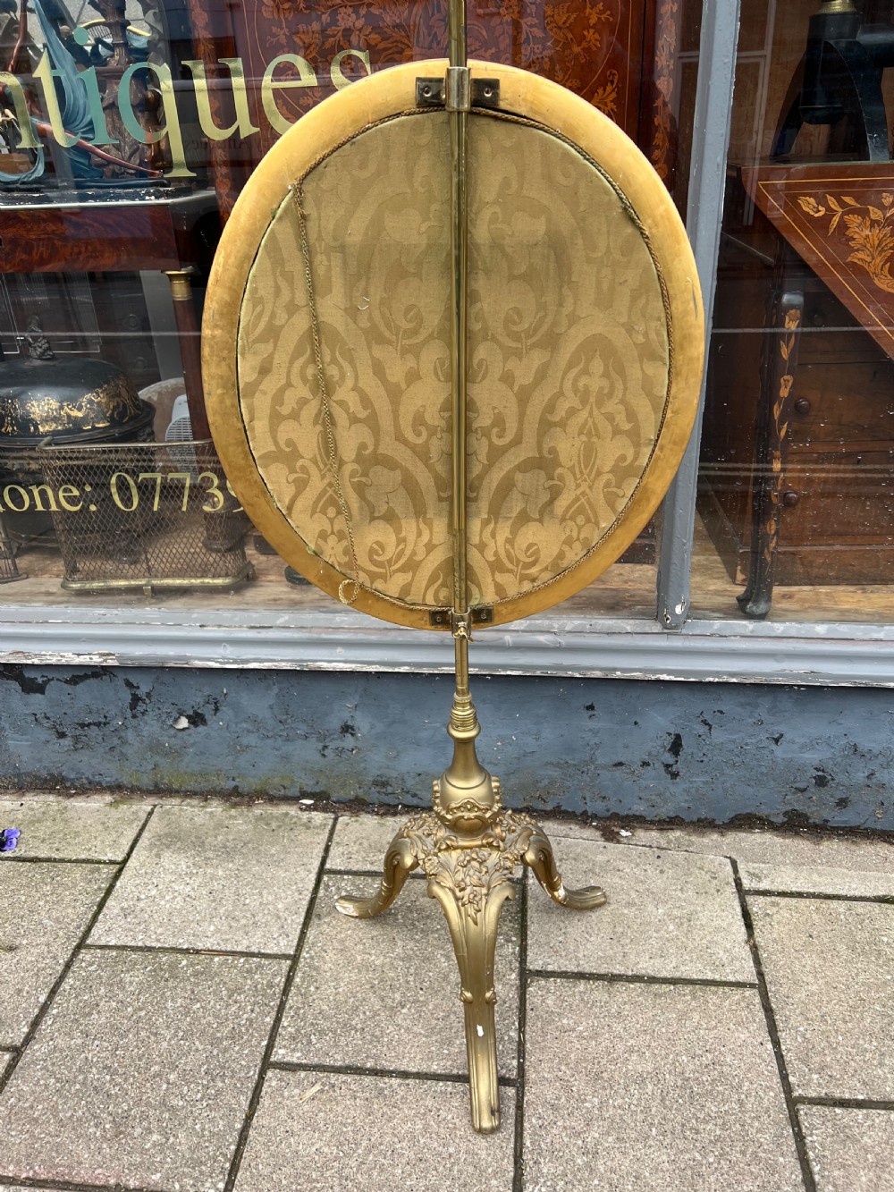 A 19th-century gilded pole screen with a tripod Rococo base framing an oval needlepoint panel depicting flowers and a bird. View VII