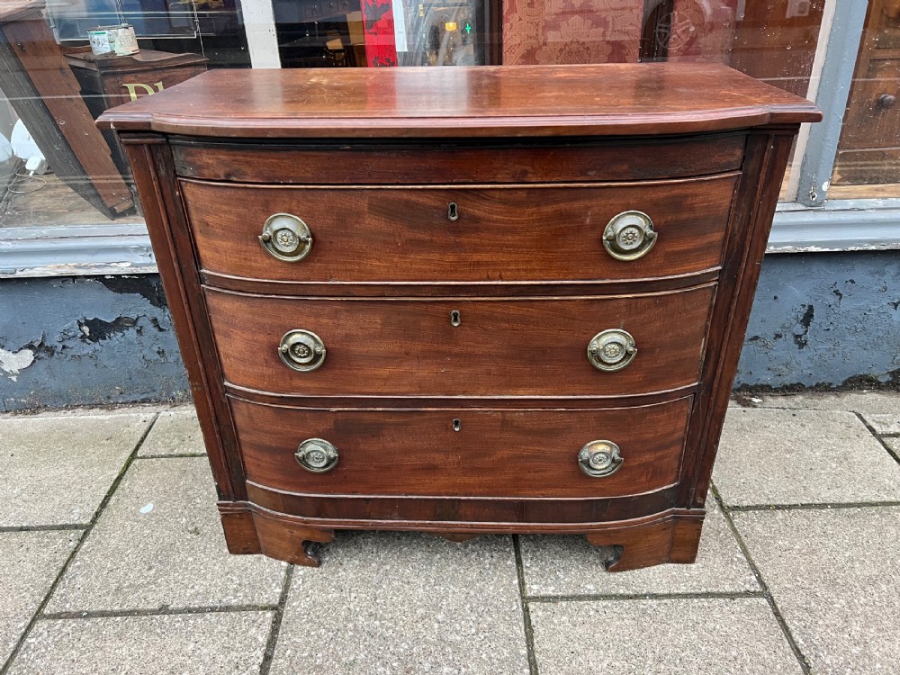 A small Georgian mahogany bow-front chest of three drawers featuring circular brass ring pulls and bracket feet. View II