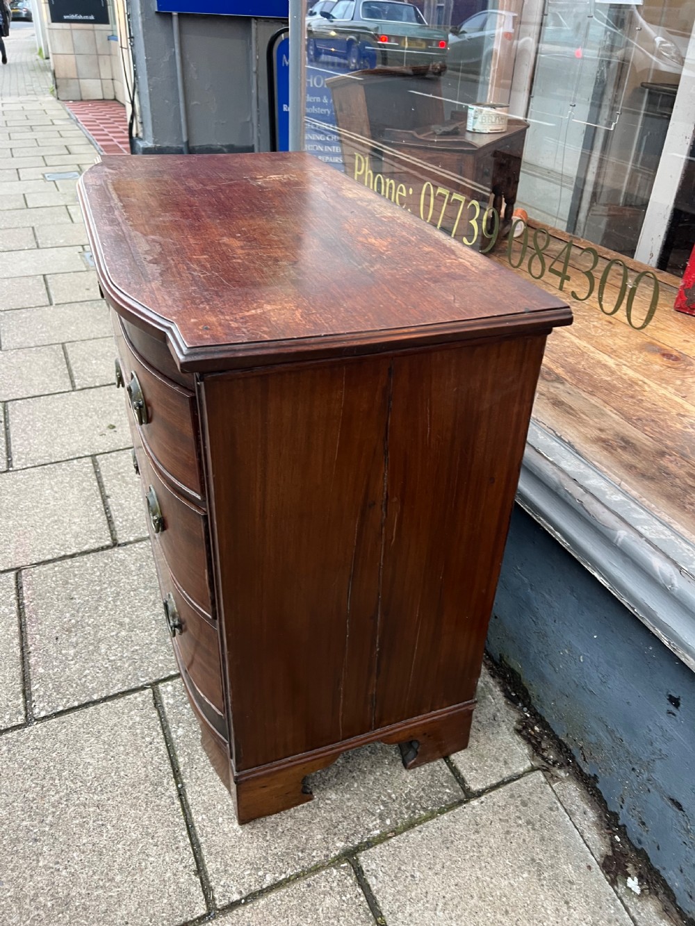 A small Georgian mahogany bow-front chest of three drawers featuring circular brass ring pulls and bracket feet. View III