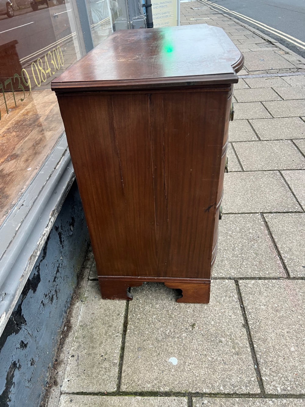 A small Georgian mahogany bow-front chest of three drawers featuring circular brass ring pulls and bracket feet. View V