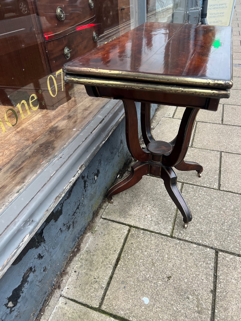 A Regency mahogany card table with brass edging, fold-over top, and quadform pedestal base on castors. View III