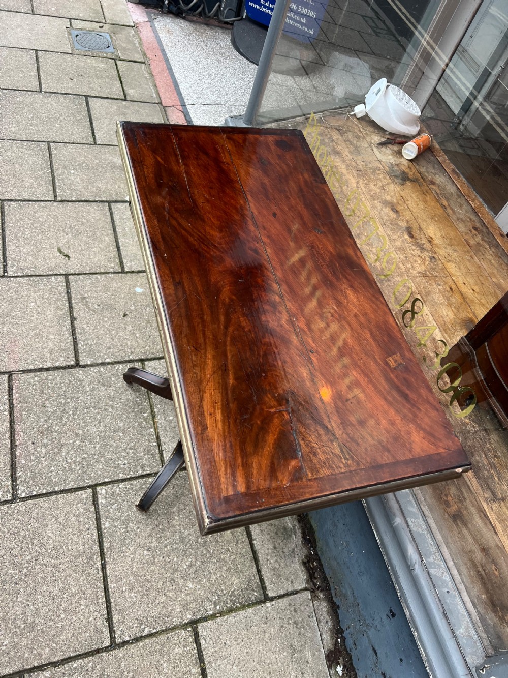 A Regency mahogany card table with brass edging, fold-over top, and quadform pedestal base on castors. View IV