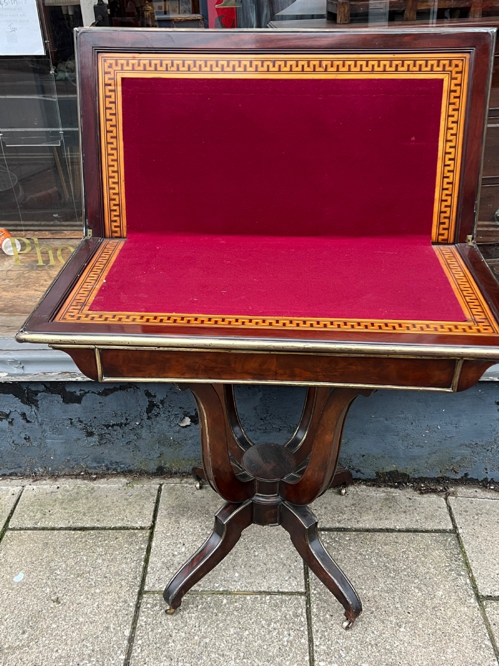 A Regency mahogany card table with brass edging, fold-over top, and quadform pedestal base on castors. View VI