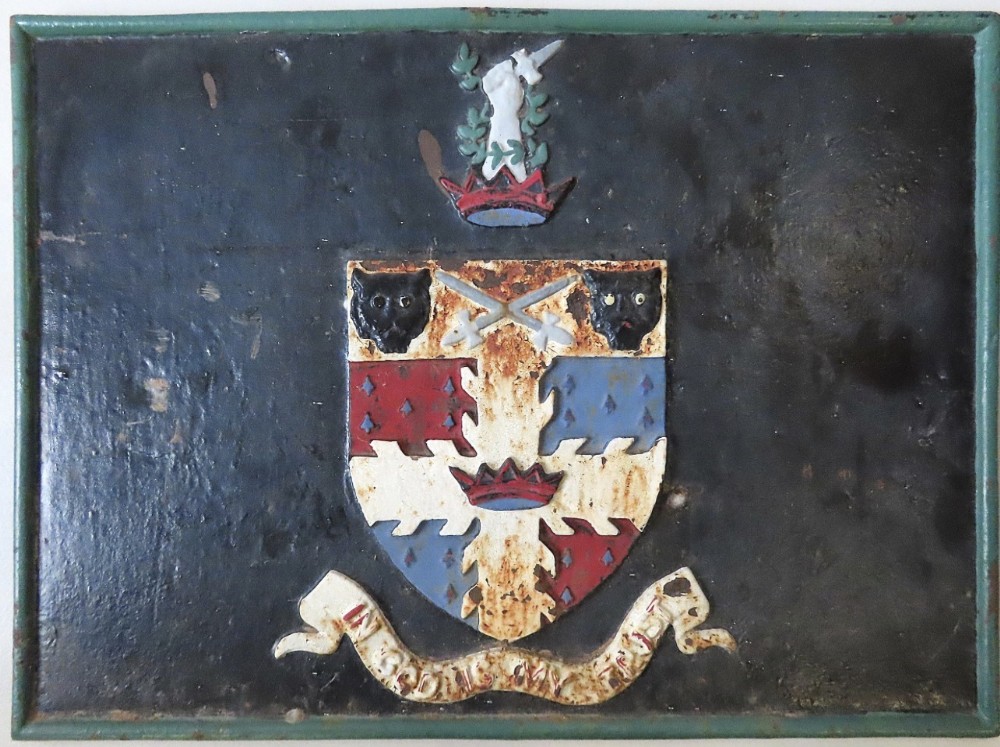 A rectangular dark cast iron wall plaque featuring a raised heraldic coat of arms with a shield, crown crest, and lower motto scroll in polychrome paint.