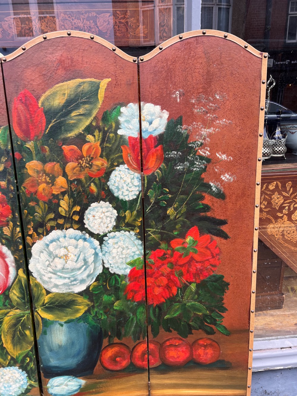 A four-panel arched folding screen featuring a large hand-painted floral still life in a blue vase set on a wooden table surface against a warm brown background. View II
