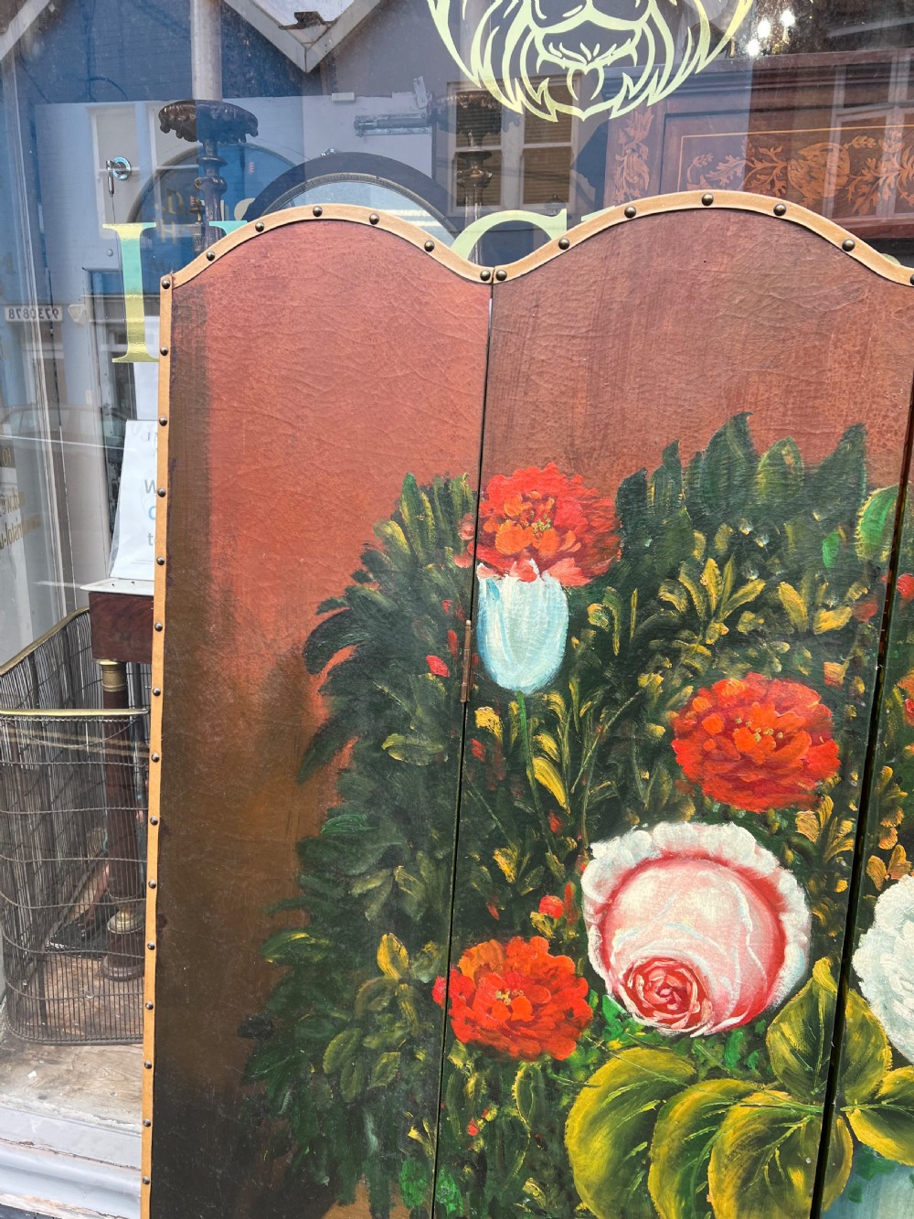 A four-panel arched folding screen featuring a large hand-painted floral still life in a blue vase set on a wooden table surface against a warm brown background. View IV