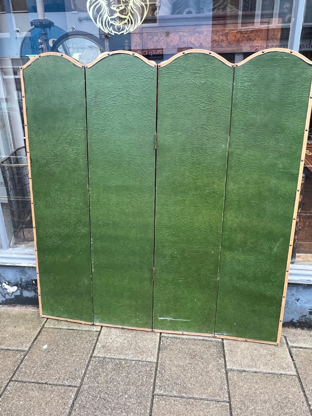A four-panel arched folding screen featuring a large hand-painted floral still life in a blue vase set on a wooden table surface against a warm brown background. View V