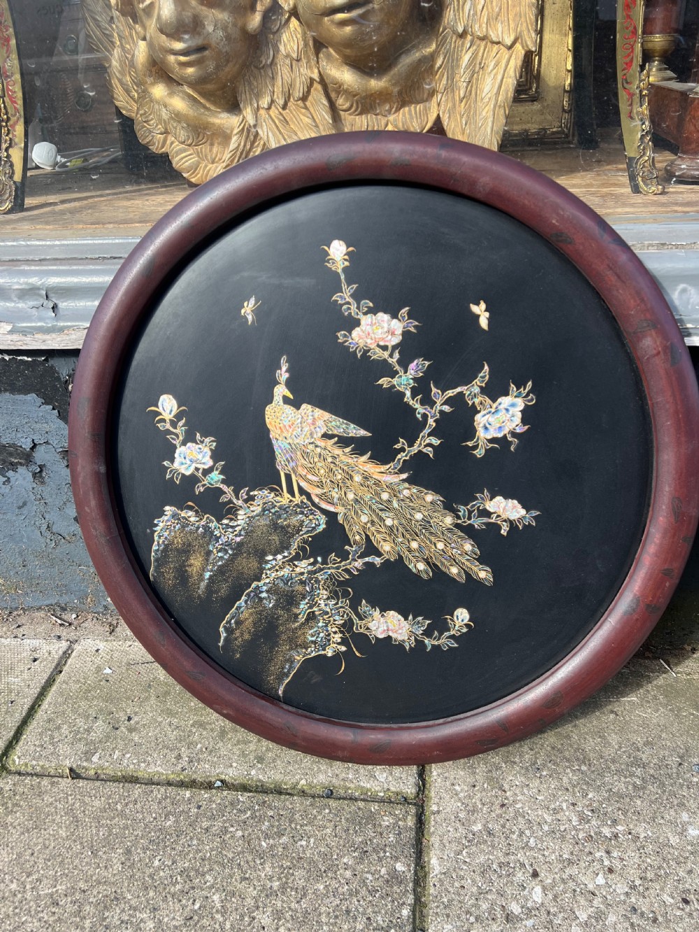A pair of circular black lacquered wall plaques set in dark wood frames, decorated with mother-of-pearl and bone inlays depicting a peacock amongst foliage and a bird in flight over water. View III