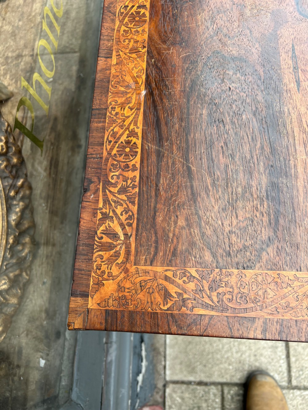 A Regency period rosewood fold-over tea table featuring intricate floral inlay along the border, resting on a pedestal base with four carved paw feet on castors. View II