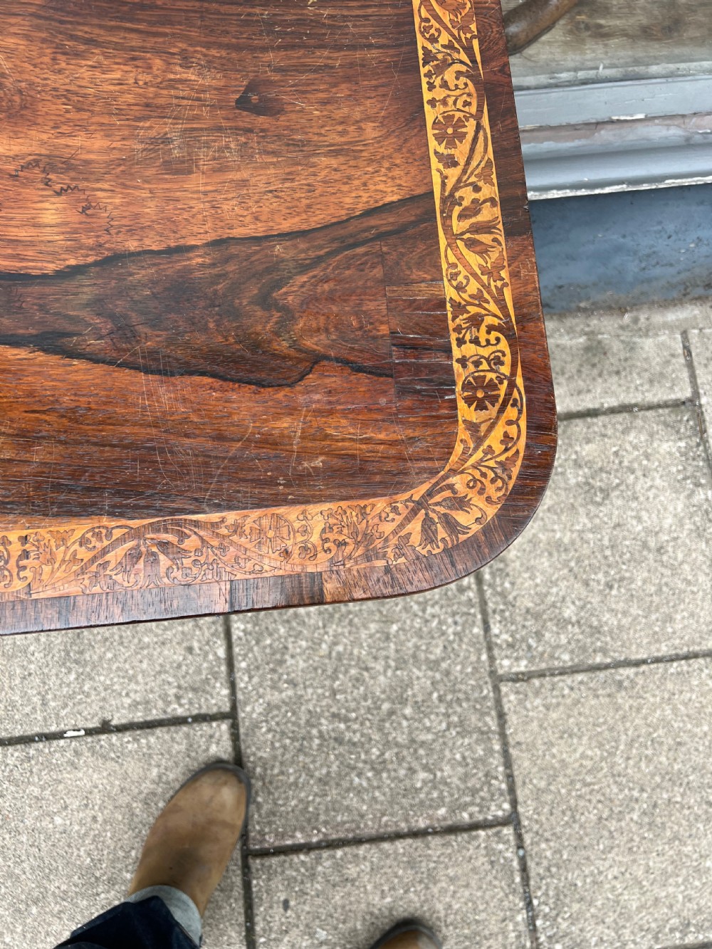 A Regency period rosewood fold-over tea table featuring intricate floral inlay along the border, resting on a pedestal base with four carved paw feet on castors. View IV