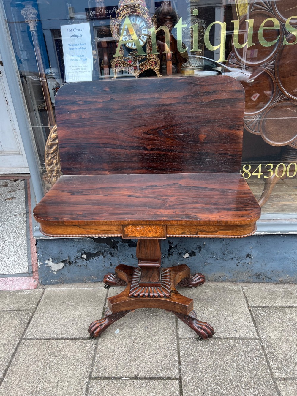 A Regency period rosewood fold-over tea table featuring intricate floral inlay along the border, resting on a pedestal base with four carved paw feet on castors. View XI