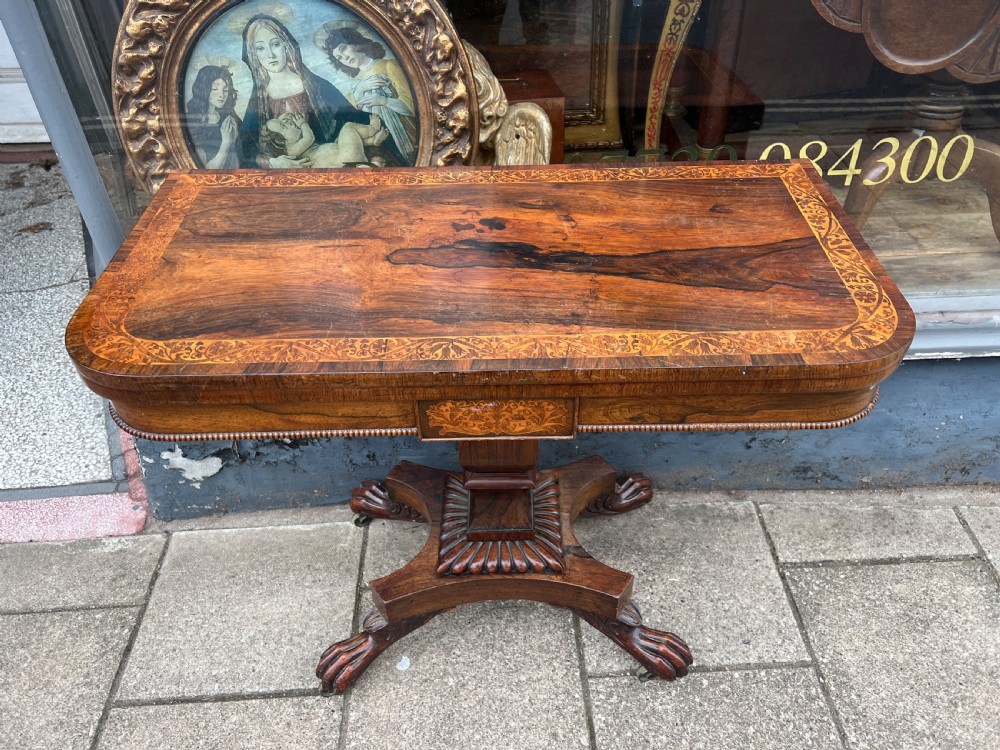 A Regency period rosewood fold-over tea table featuring intricate floral inlay along the border, resting on a pedestal base with four carved paw feet on castors. View XII