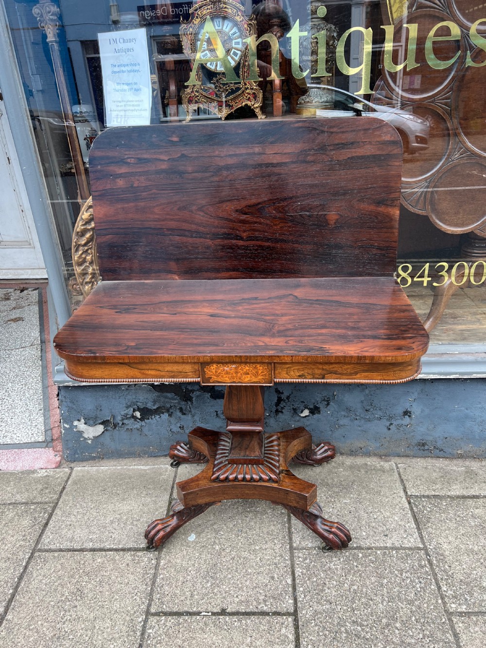 A Regency period rosewood fold-over tea table featuring intricate floral inlay along the border, resting on a pedestal base with four carved paw feet on castors. View XIII