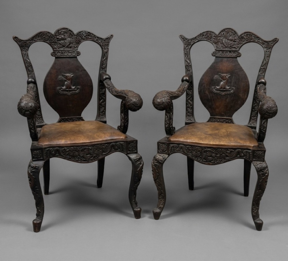 A pair of early C19th Chinese armchairs with crest to centre 
