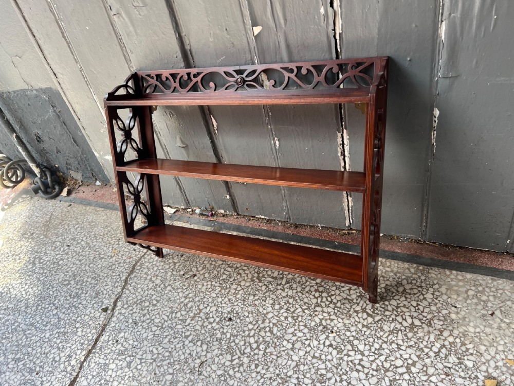 A three-tier dark mahogany wall shelf featuring decorative lattice fretwork side panels and a carved top gallery. View V
