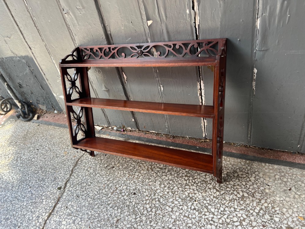 A three-tier dark mahogany wall shelf featuring decorative lattice fretwork side panels and a carved top gallery. View VI