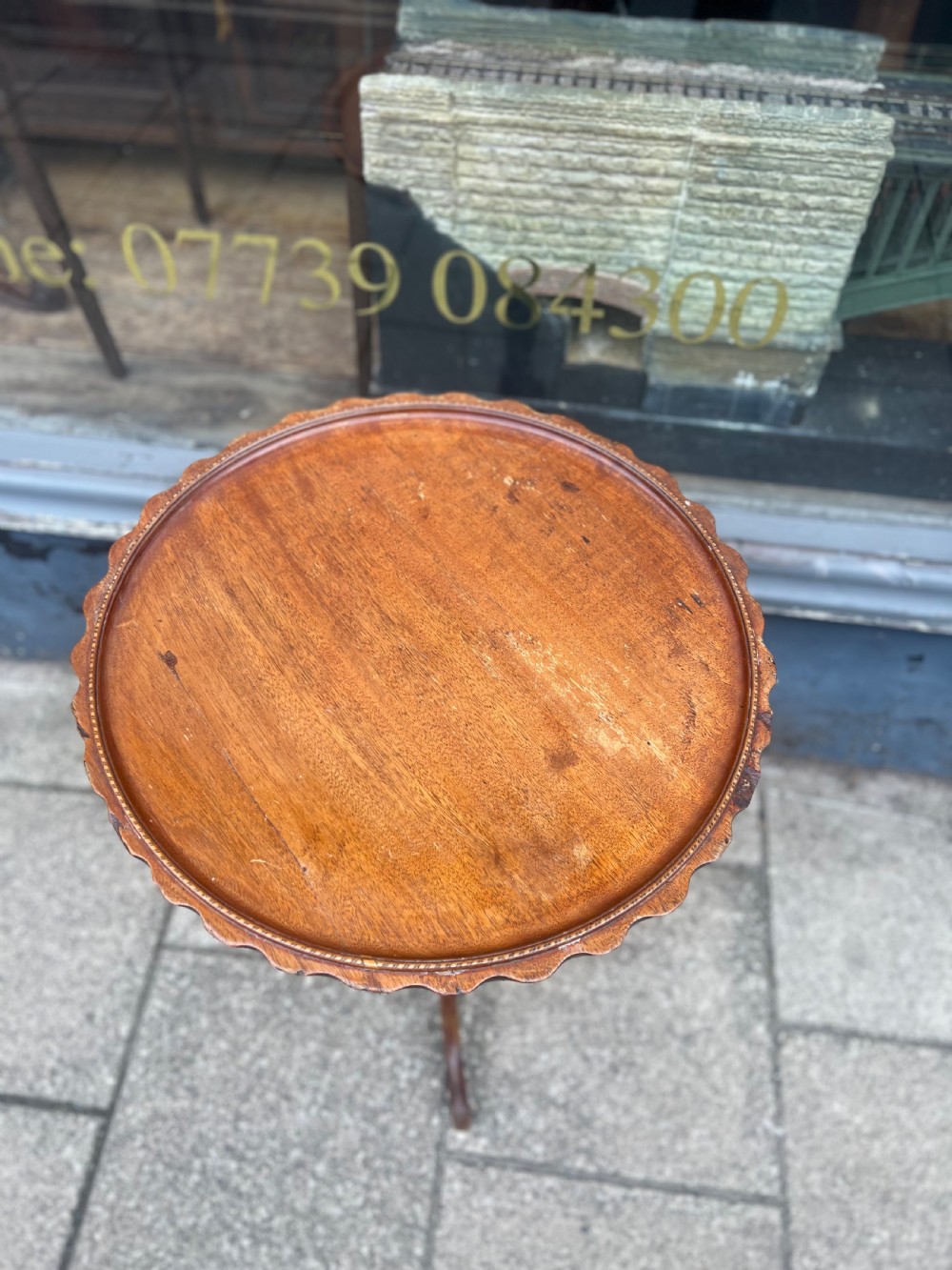 A nineteenth-century dark wood tripod wine table featuring a scalloped rim top, a turned central column, and three cabriole legs. View V