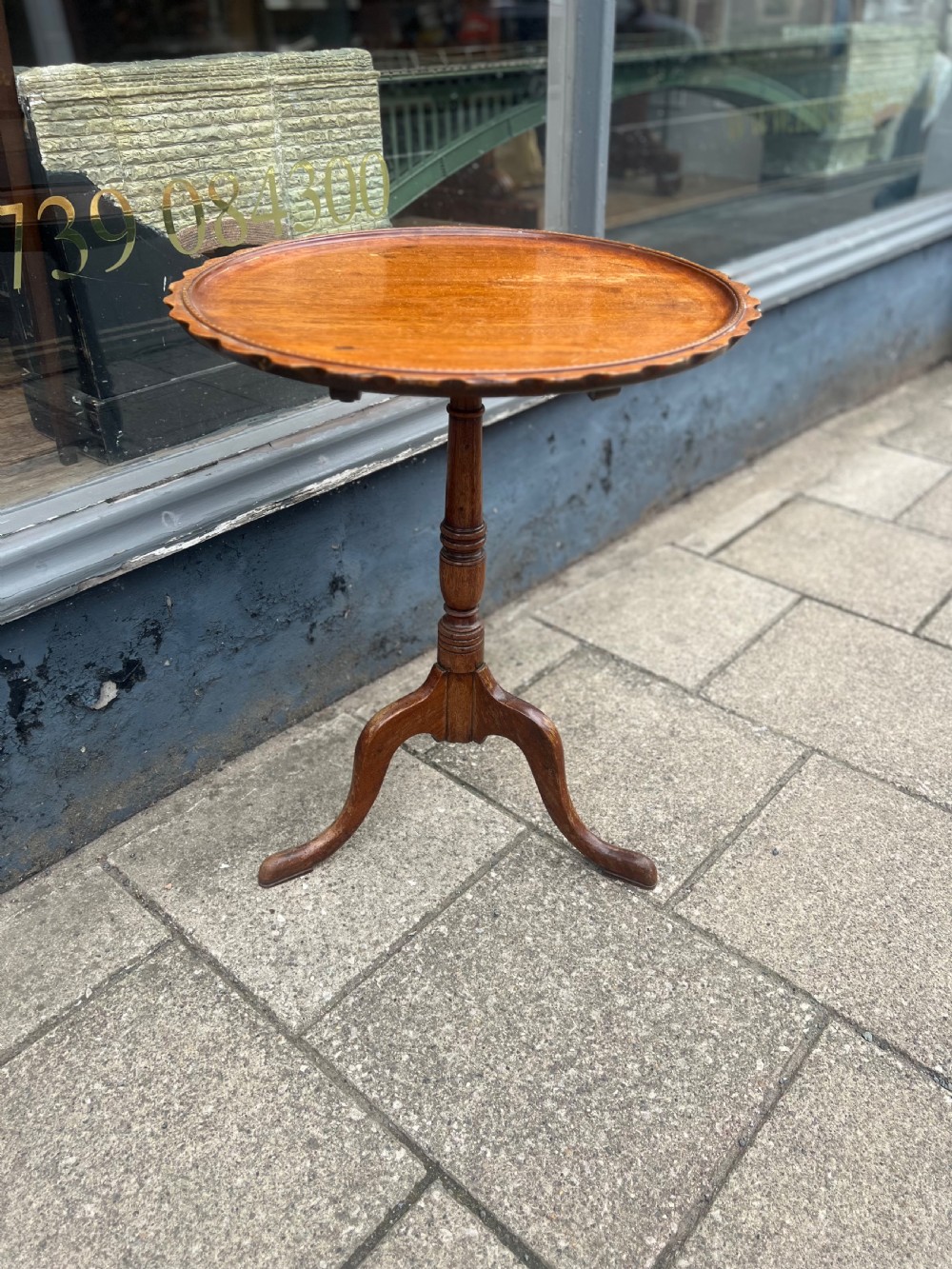 A nineteenth-century dark wood tripod wine table featuring a scalloped rim top, a turned central column, and three cabriole legs. View VI