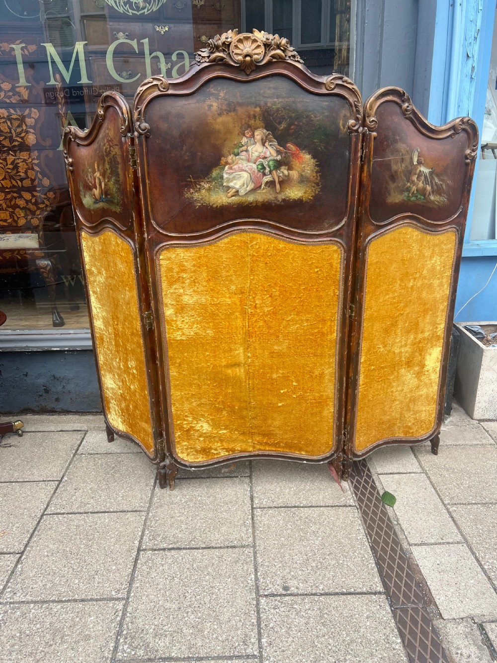 A three-panel French modesty screen featuring carved timber frames with oil-painted pastoral scenes on the upper panels and gold velvet upholstery on the lower panels. View IV