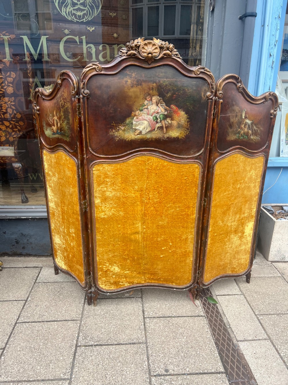 A three-panel French modesty screen featuring carved timber frames with oil-painted pastoral scenes on the upper panels and gold velvet upholstery on the lower panels. View V