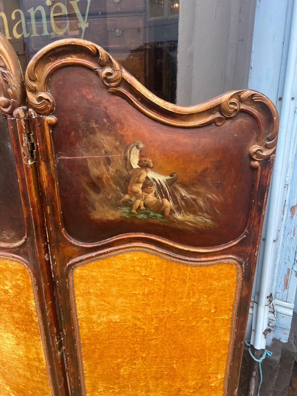 A three-panel French modesty screen featuring carved timber frames with oil-painted pastoral scenes on the upper panels and gold velvet upholstery on the lower panels. View VI