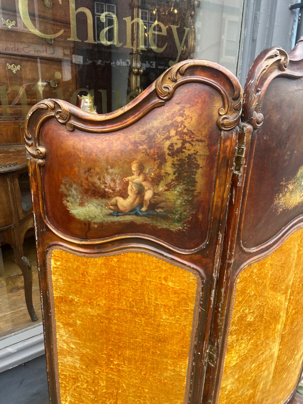 A three-panel French modesty screen featuring carved timber frames with oil-painted pastoral scenes on the upper panels and gold velvet upholstery on the lower panels. View VII