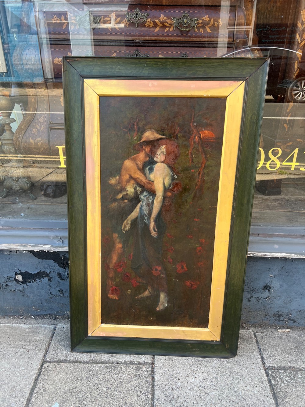 A vertical oil painting on canvas depicting two figures embracing amongst red poppies, housed in a wide green timber frame with a gilt inner slip. View III
