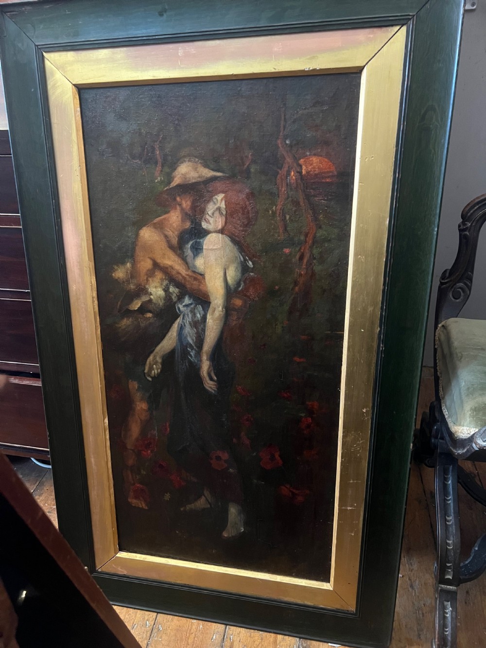 A vertical oil painting on canvas depicting two figures embracing amongst red poppies, housed in a wide green timber frame with a gilt inner slip. View V