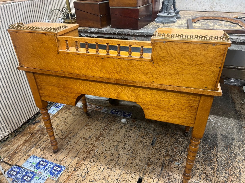 An antique birds eye maple writing desk featuring a black leather surface, turned legs on castors, and an upper superstructure with small drawers and a brass gallery railing. View IV