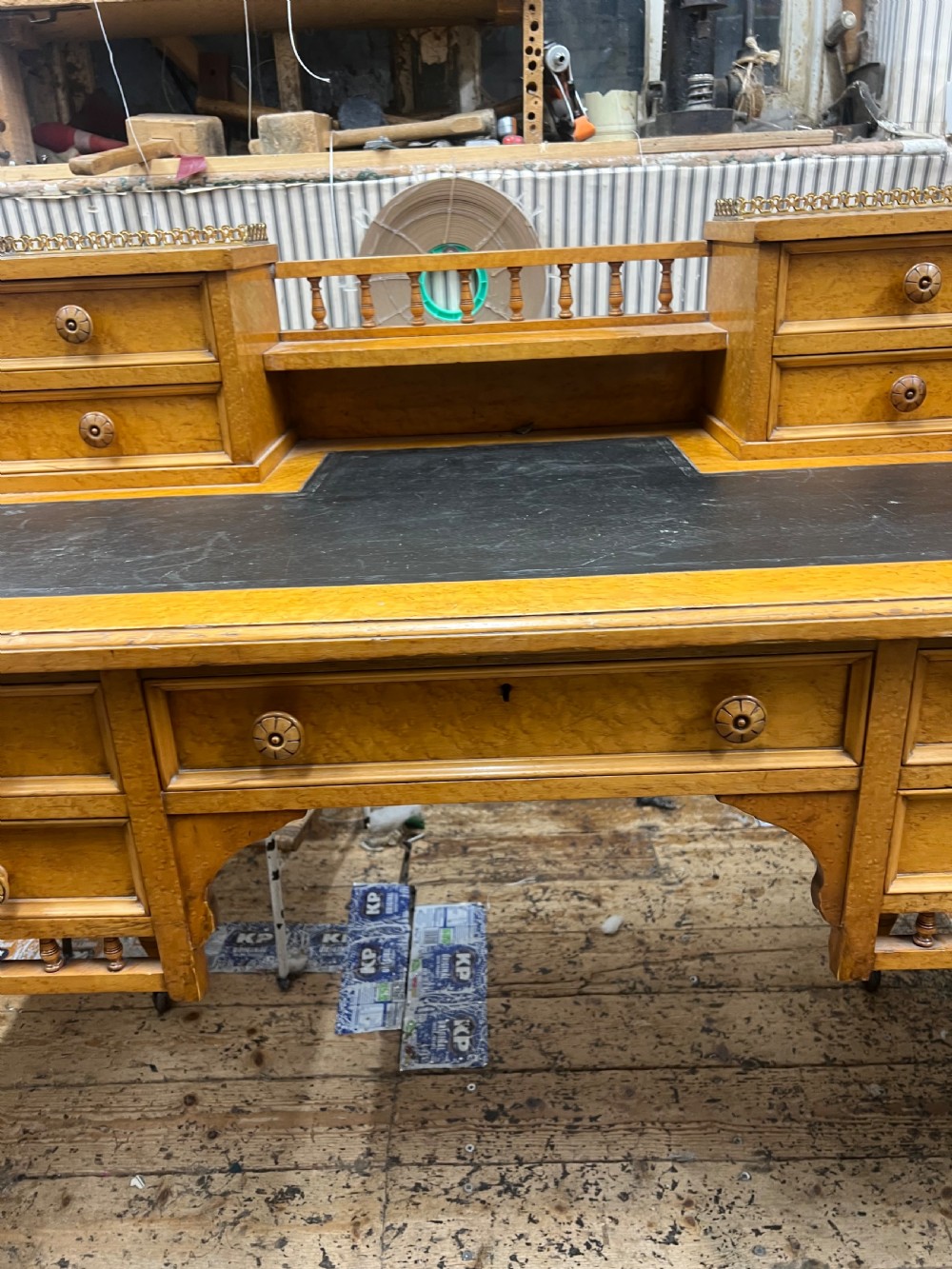 An antique birds eye maple writing desk featuring a black leather surface, turned legs on castors, and an upper superstructure with small drawers and a brass gallery railing. View VIII