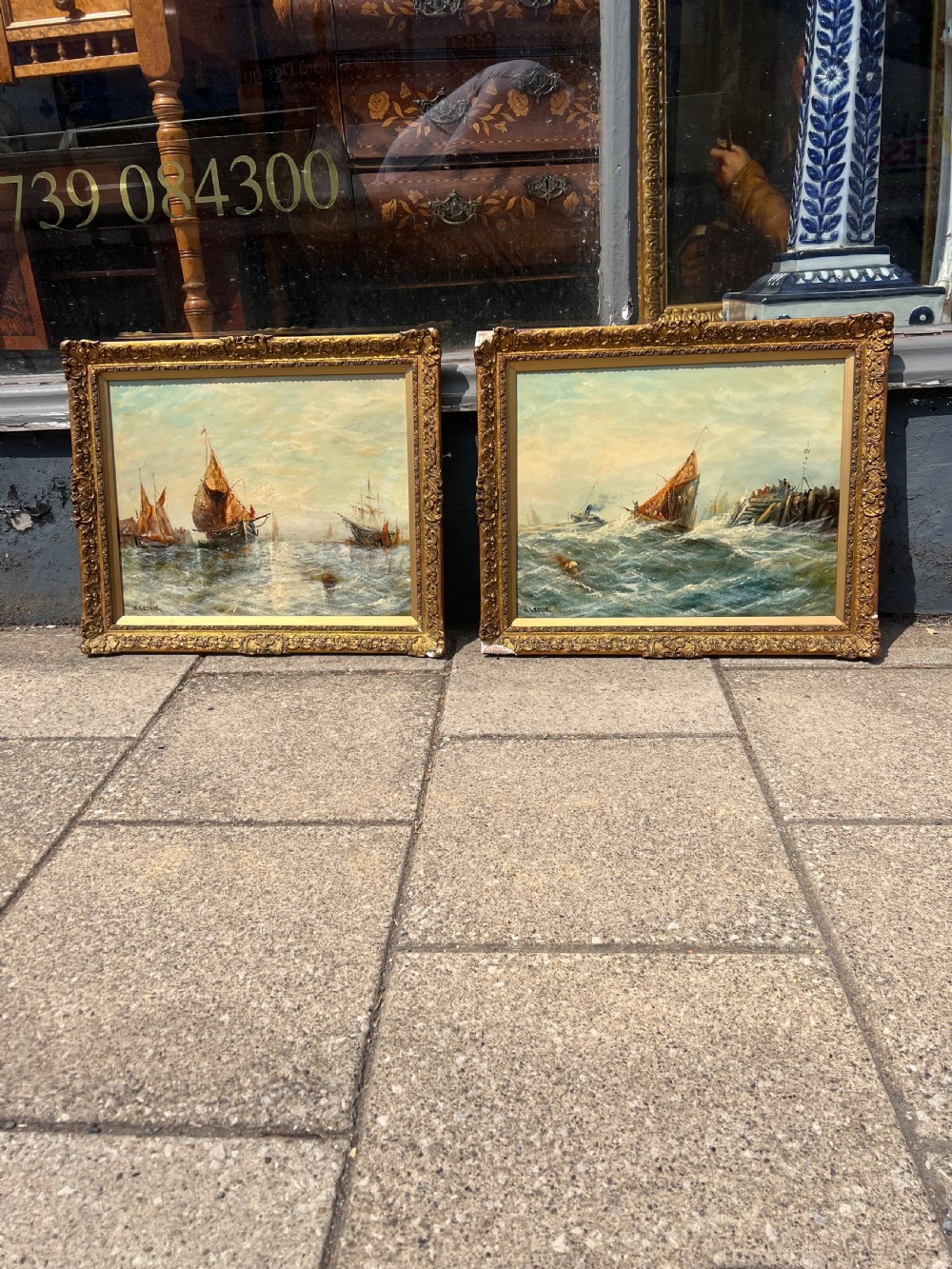 A pair of antique oil paintings on board depicting sailing ships on choppy waters, framed in ornate gold gilt frames. View IV