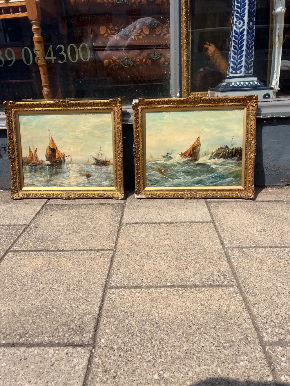 A pair of antique oil paintings on board depicting sailing ships on choppy waters, framed in ornate gold gilt frames. View V