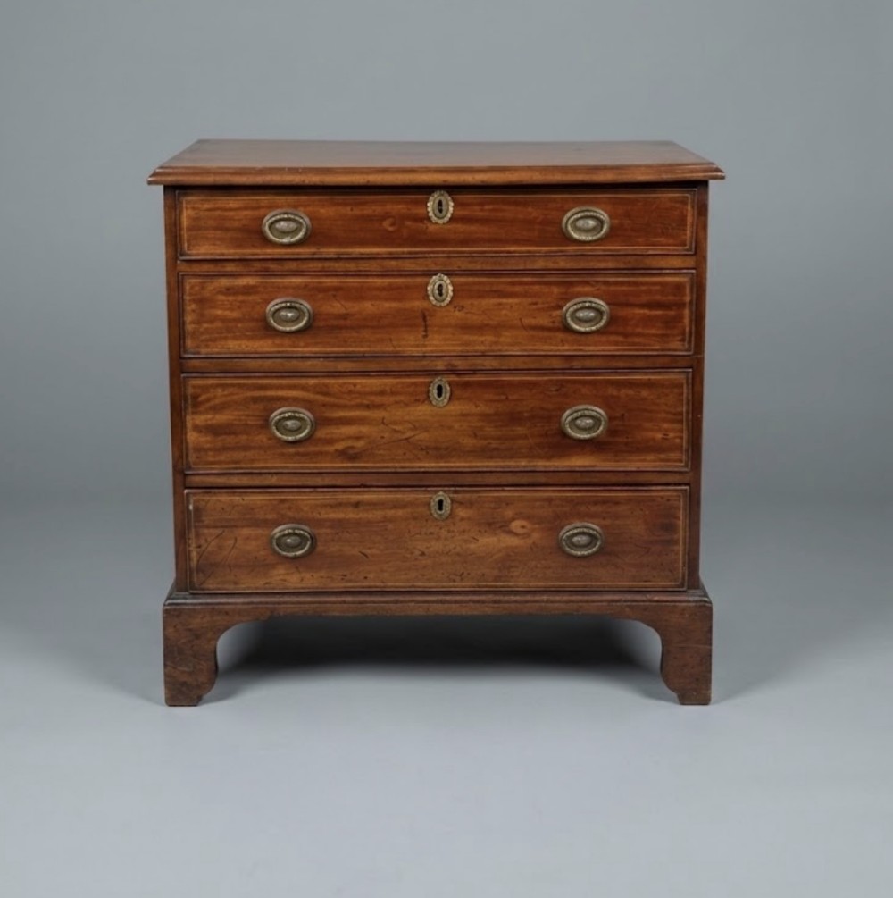 A Georgian mahogany chest of drawers with four full-width drawers, oval brass handles, brass escutcheons, and bracket feet.