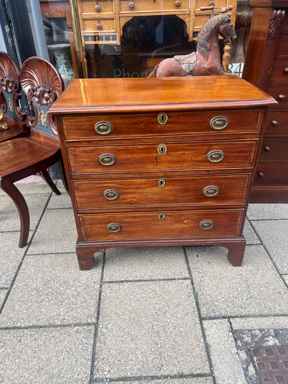 A Georgian mahogany chest of drawers with four full-width drawers, oval brass handles, brass escutcheons, and bracket feet. View II