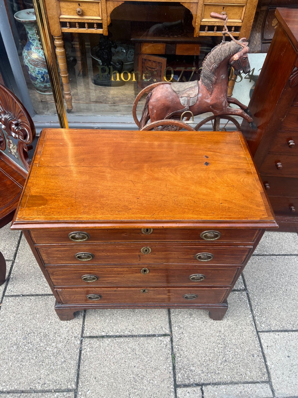 A Georgian mahogany chest of drawers with four full-width drawers, oval brass handles, brass escutcheons, and bracket feet. View IV