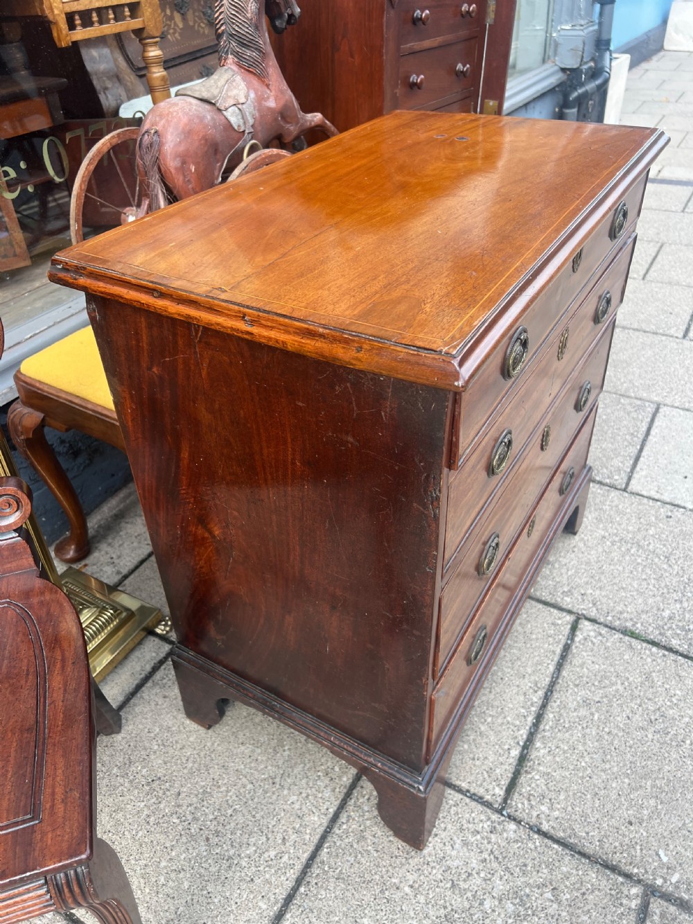 A Georgian mahogany chest of drawers with four full-width drawers, oval brass handles, brass escutcheons, and bracket feet. View V