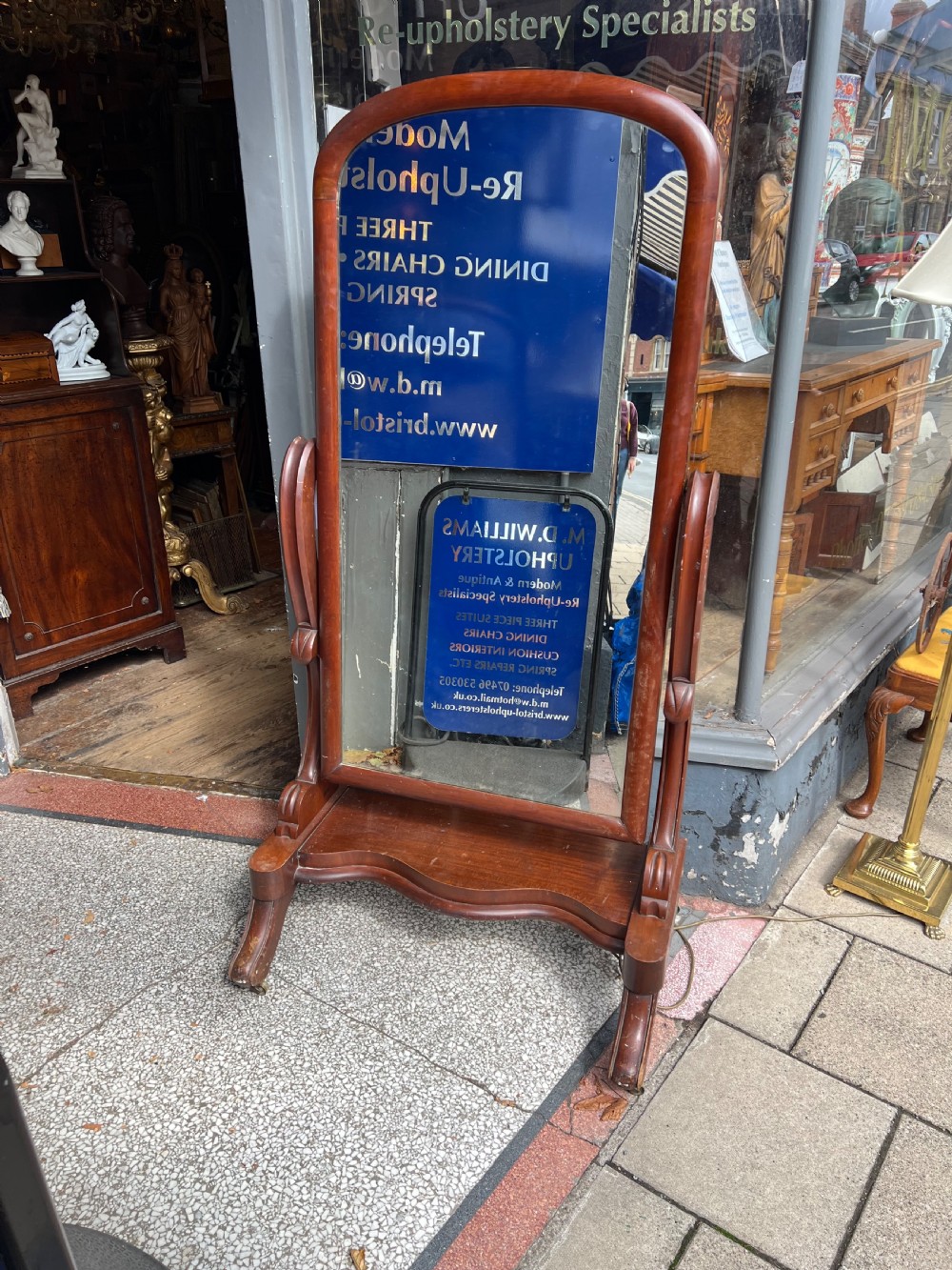 A Victorian mahogany full-length cheval mirror featuring an arched frame, carved scroll upright supports, and a shaped plinth base on carved legs. View II