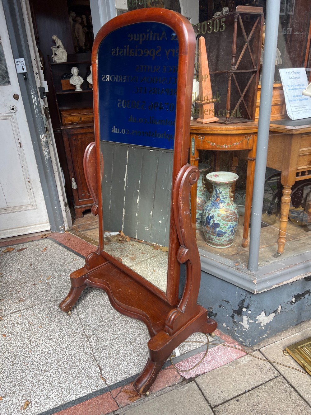A Victorian mahogany full-length cheval mirror featuring an arched frame, carved scroll upright supports, and a shaped plinth base on carved legs. View III