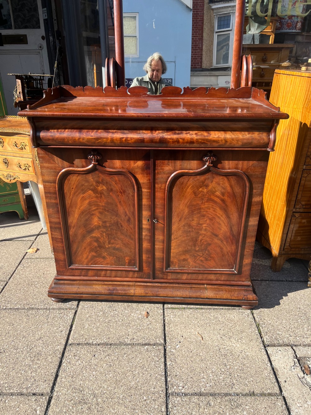 A William IV flame mahogany side cabinet with twin arch-panelled doors, a cushion frieze drawer, and a shaped gallery top rail. View III