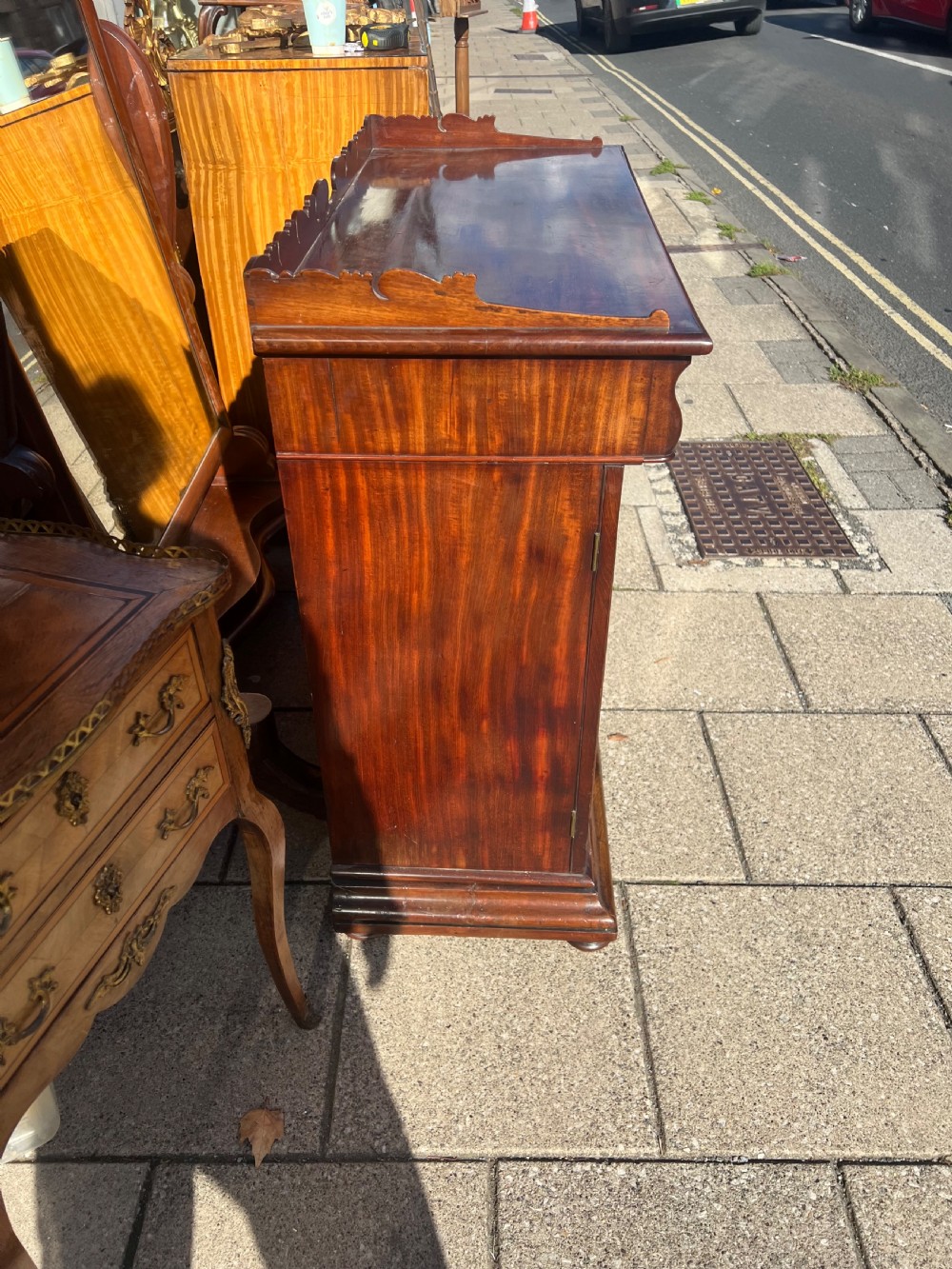 A William IV flame mahogany side cabinet with twin arch-panelled doors, a cushion frieze drawer, and a shaped gallery top rail. View V