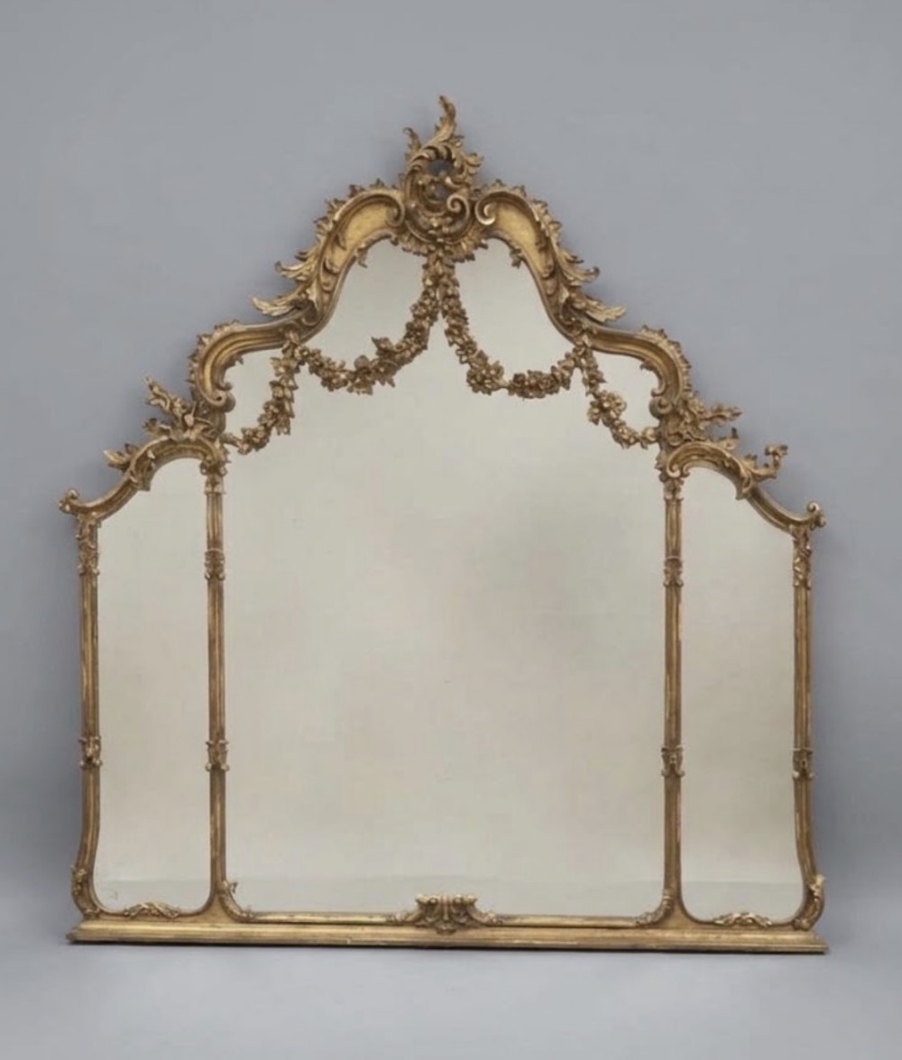 An early twentieth-century giltwood overmantel mirror featuring a tripartite three-plate design, floral garlands, and a carved acanthus crest.