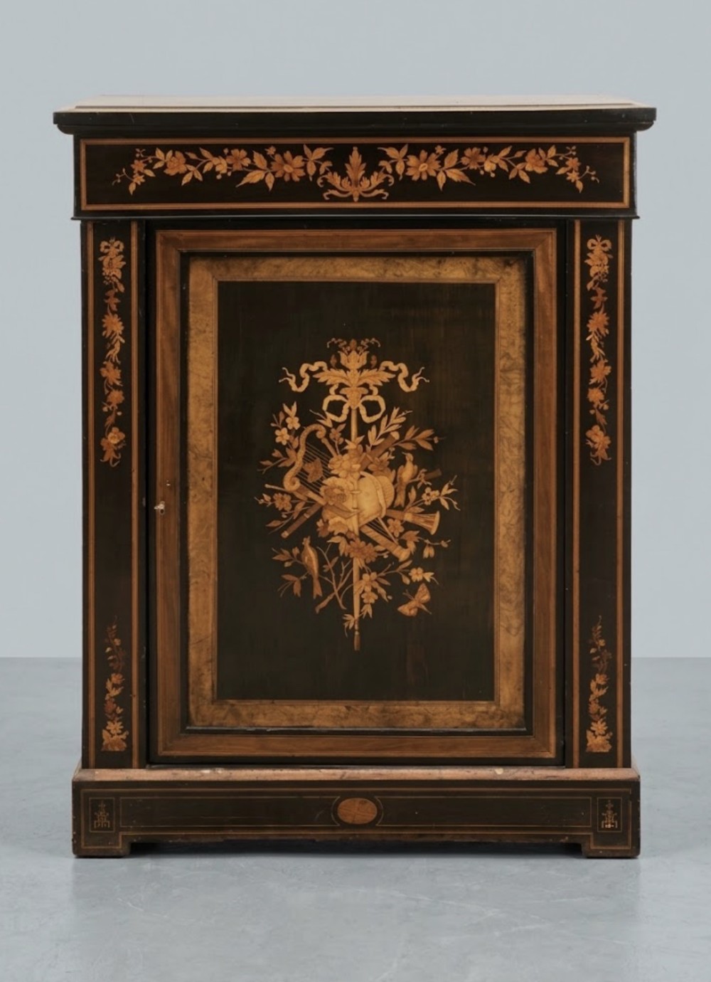 A dark ebonised side cabinet featuring floral and musical instrument marquetry inlay on a single panelled door.