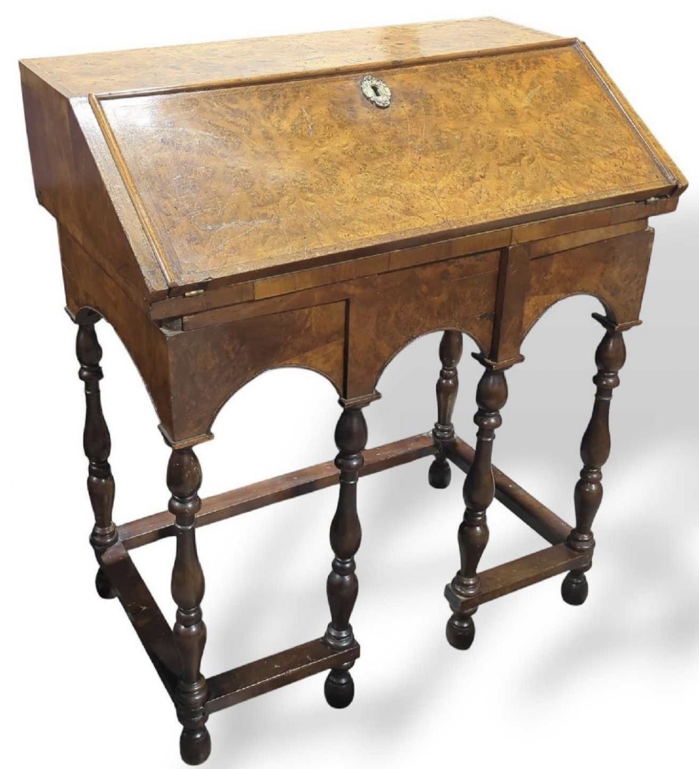 An early 18th-century walnut slant-front bureau on a base supported by six turned baluster legs with perimeter stretchers.
