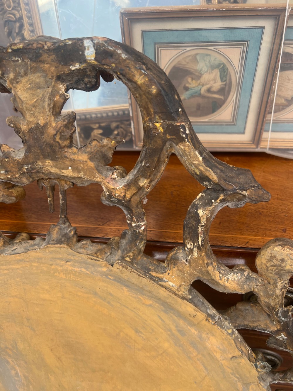 An 18th-century style oval wall mirror featuring a carved giltwood frame with openwork scrollwork and acanthus leaf cresting. View V