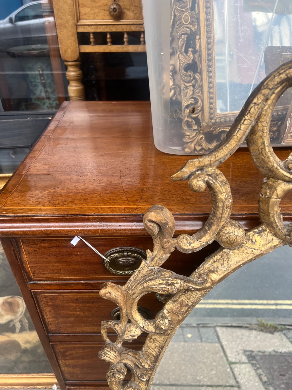 An 18th-century style oval wall mirror featuring a carved giltwood frame with openwork scrollwork and acanthus leaf cresting. View VI