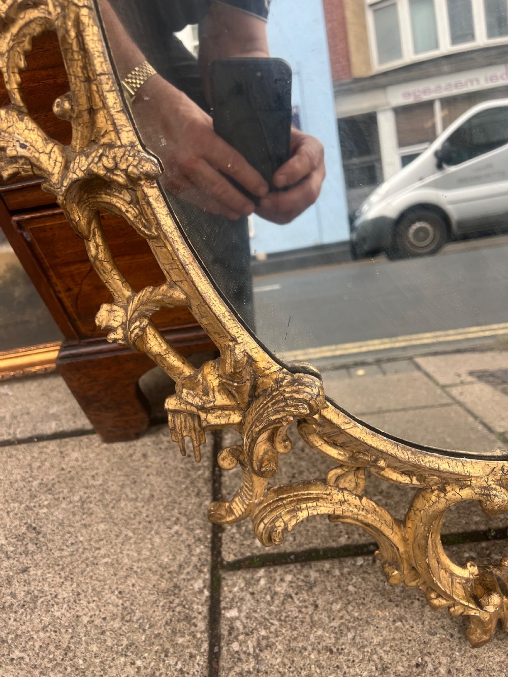 An 18th-century style oval wall mirror featuring a carved giltwood frame with openwork scrollwork and acanthus leaf cresting. View VIII