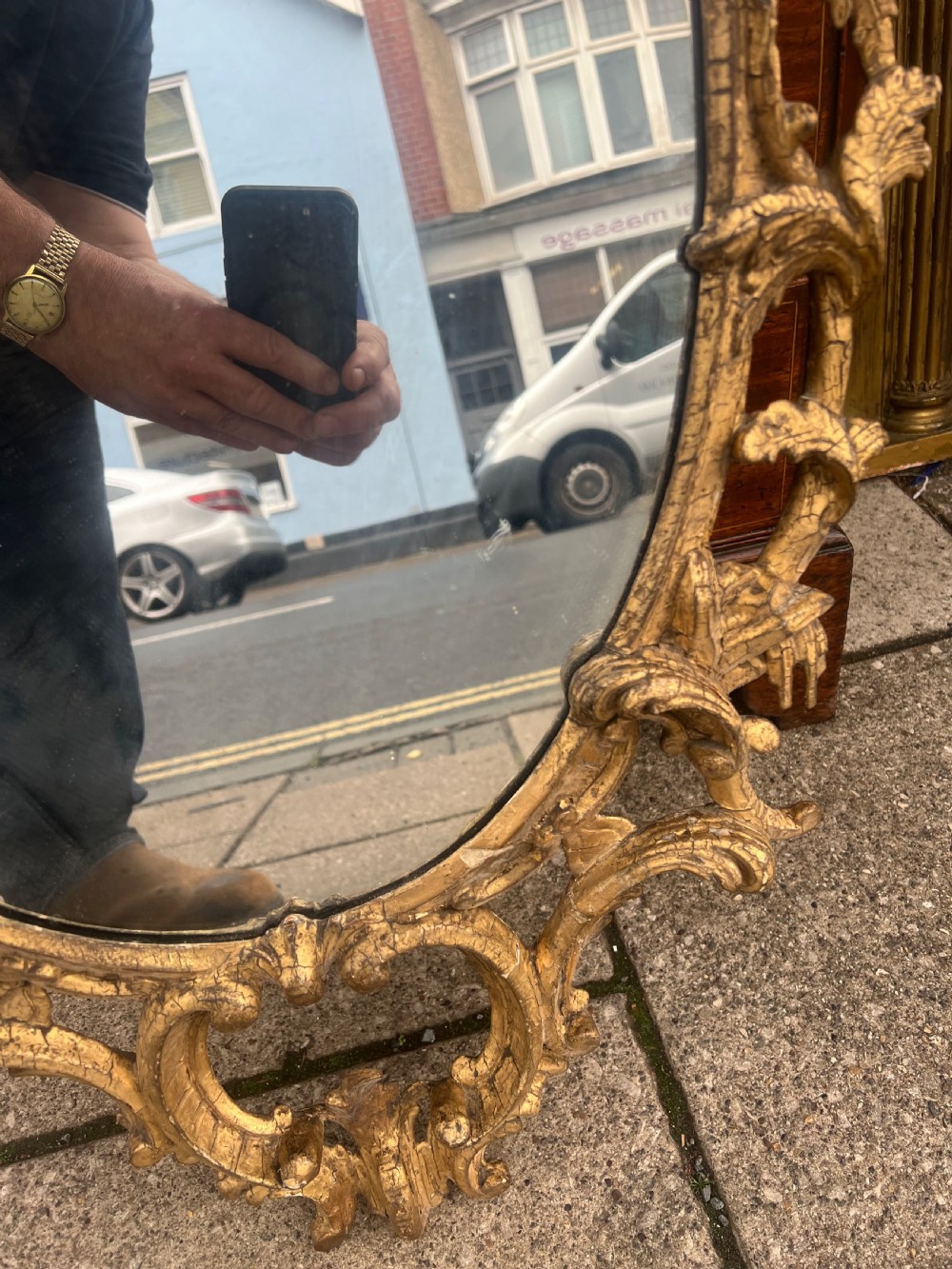 An 18th-century style oval wall mirror featuring a carved giltwood frame with openwork scrollwork and acanthus leaf cresting. View IX