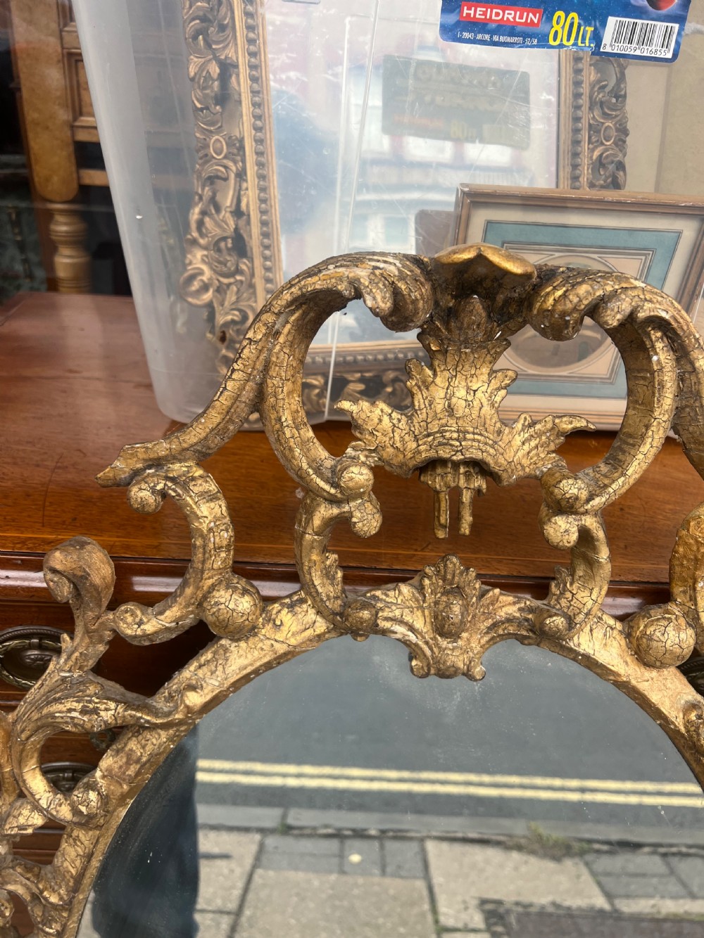 An 18th-century style oval wall mirror featuring a carved giltwood frame with openwork scrollwork and acanthus leaf cresting. View XI