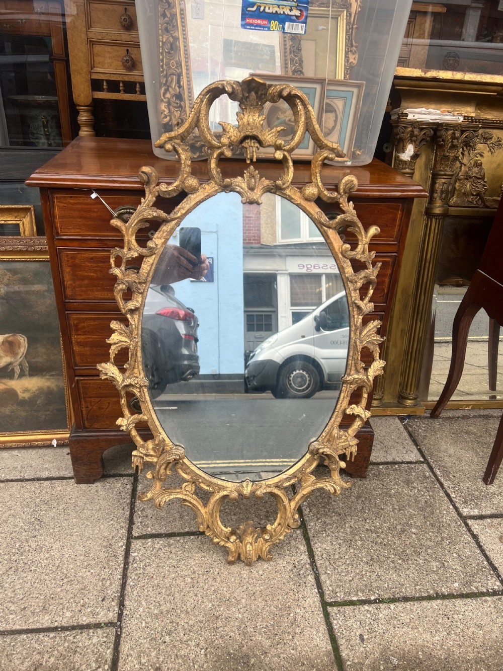An 18th-century style oval wall mirror featuring a carved giltwood frame with openwork scrollwork and acanthus leaf cresting. View XIII